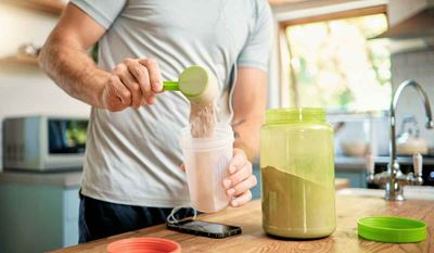 Man adds protein powder to a shake