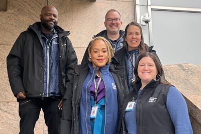 Five members of the Violence Intervention Program pose on steps to a building.