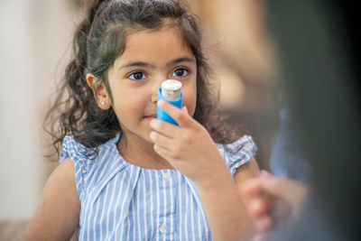 girl with asthma uses an inhaler
