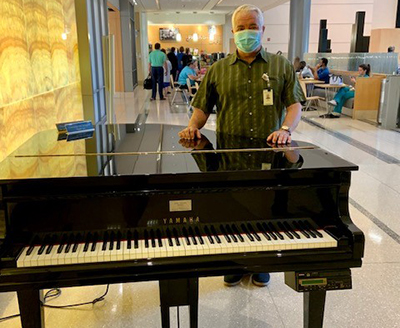 ynhh volunteer with piano in hospital lobby