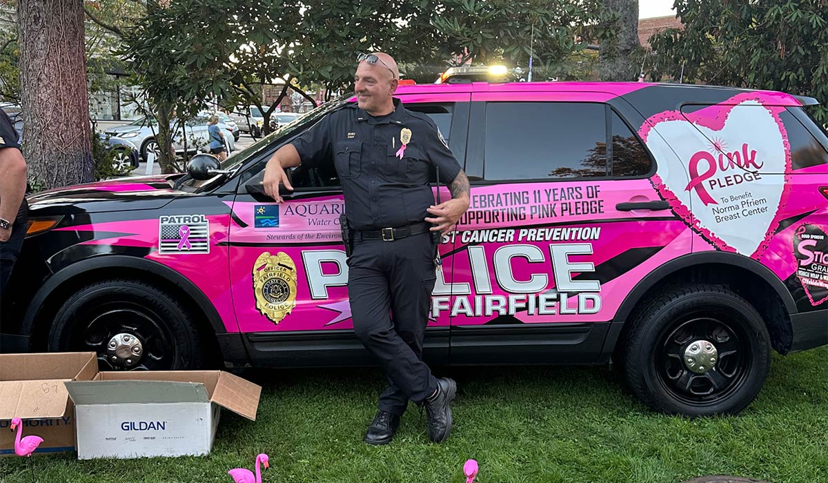 Fairfield Police Officer in front of Pink Pledge branded SUV