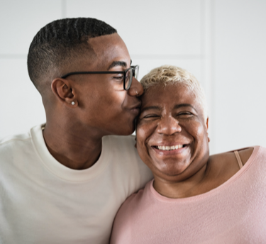 A son kissing his mother on her forehead